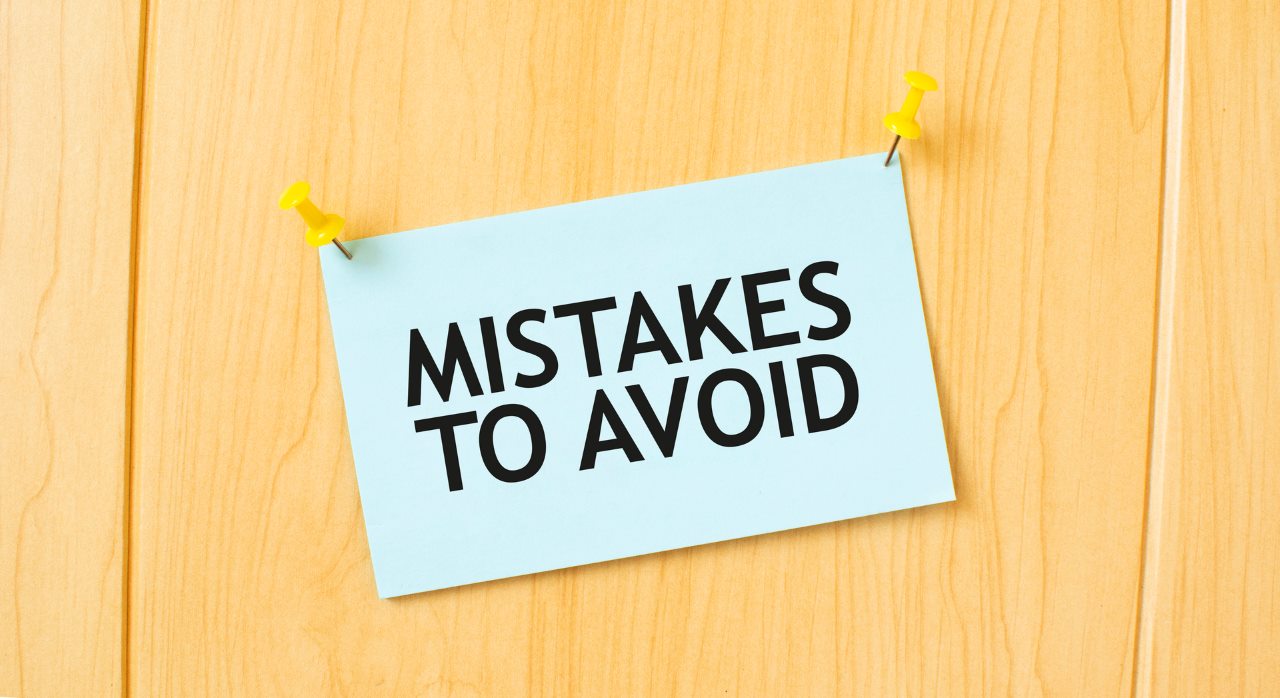 MISTAKES TO AVOID sign written on sticky note pinned on wooden wall