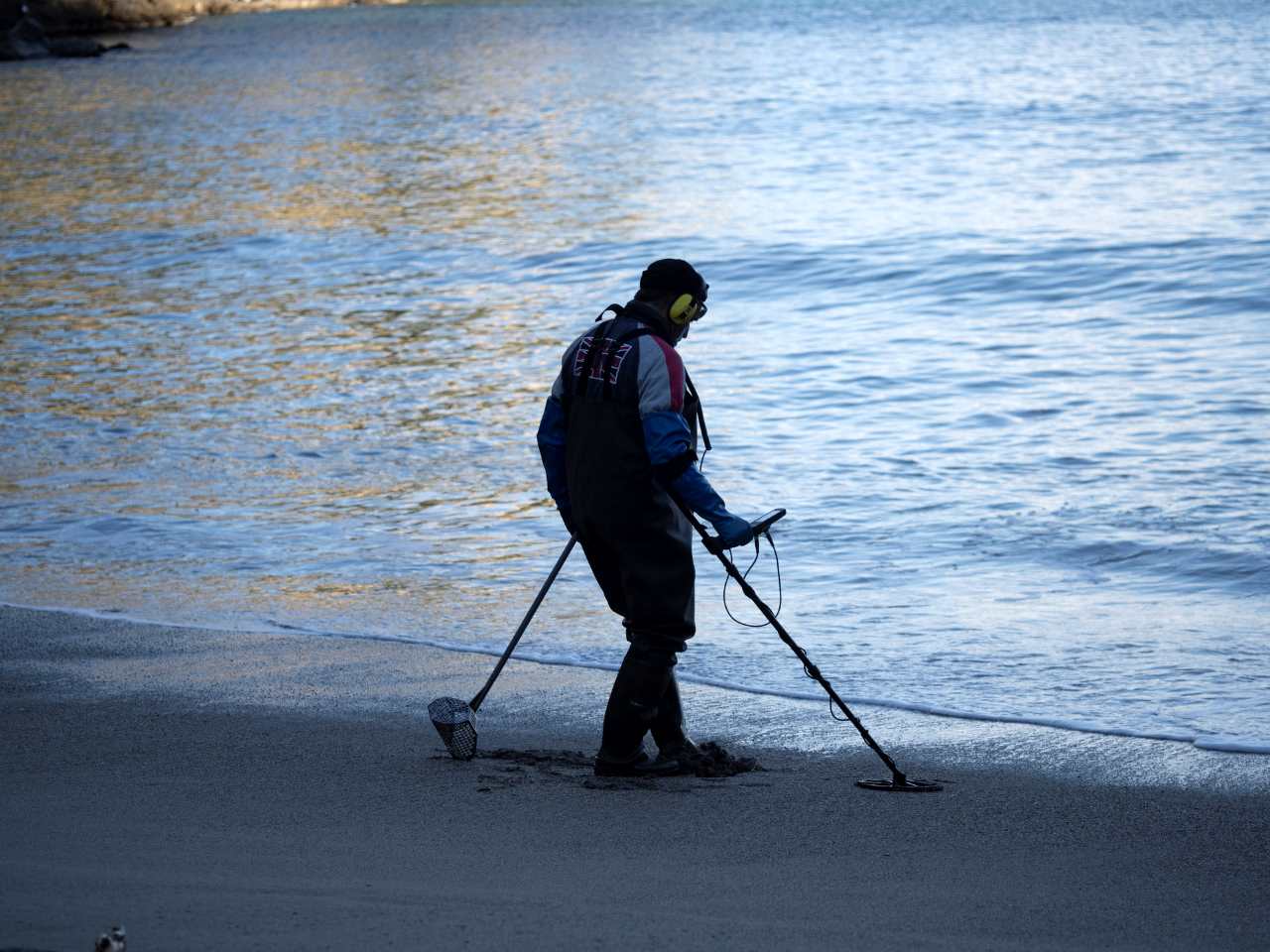 man metal detecting at a beach