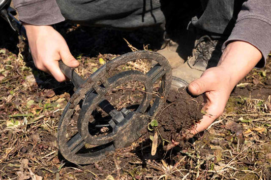 person holding a lump of soil and a metal detector